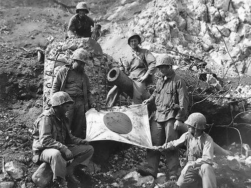 Soldados americanos segurando uma bandeira japonesa durante a Batalha de Iwo Jima
