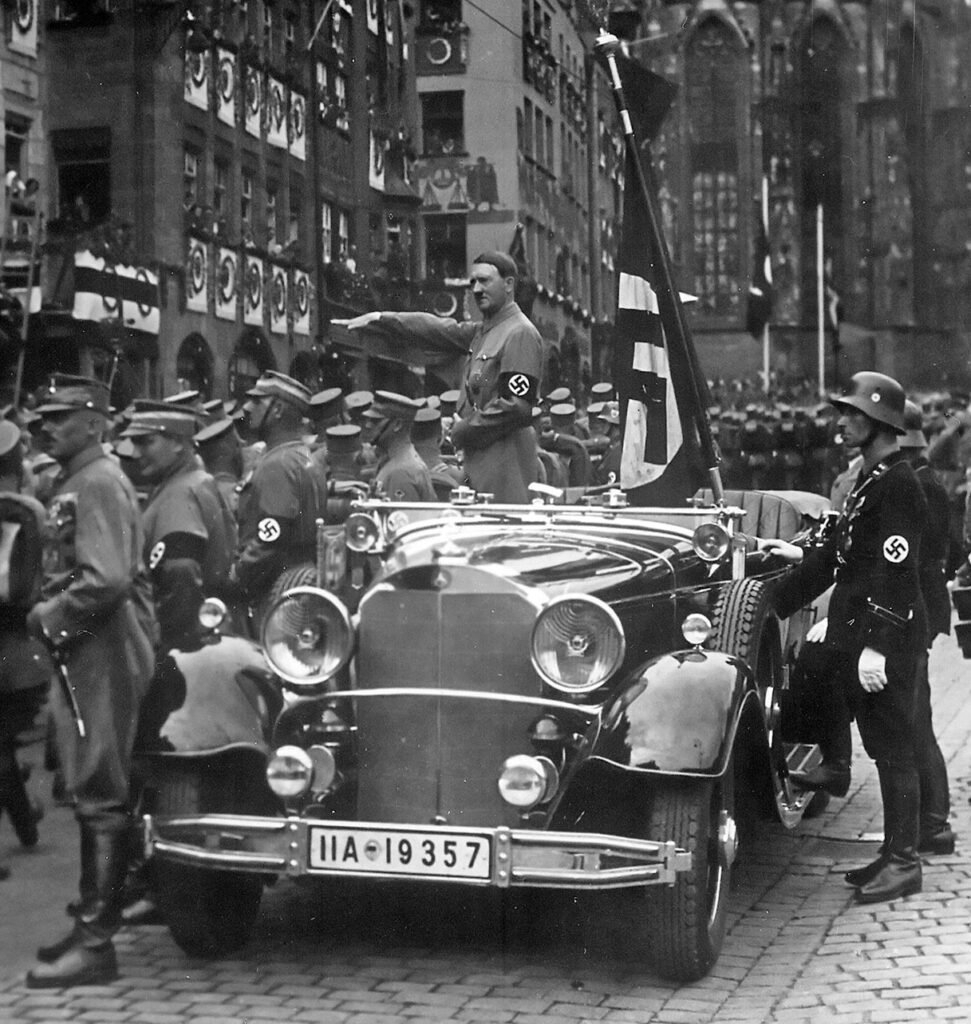 Hitler é triunfante como o Führer , revisando a SA em 1935. No carro com ele está o Blutfahne , atrás do carro o homem da SS Jakob Grimminger.