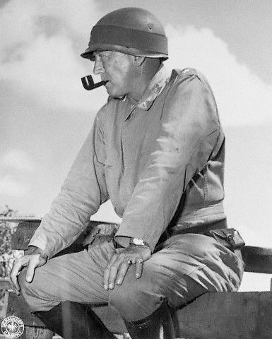 Major General George S. Patton sentado em uma cerca e fumando cachimbo enquanto observava as manobras de 1941 na Louisiana.