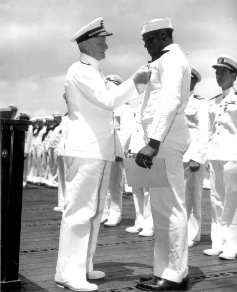 O almirante Chester W. Nimitz fixa a Cruz da Marinha em Doris "Dorie" Miller em cerimônia a bordo do USS Enterprise, Pearl Harbor, 27 de maio de 1942.