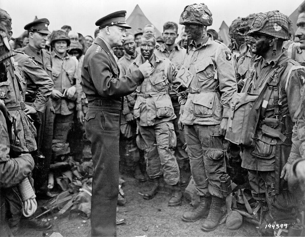 Eisenhower fala com homens do 502º Regimento de Infantaria Paraquedista (PIR), parte da 101ª Divisão Aerotransportada "Screaming Eagles" , em 5 de junho de 1944, um dia antes da invasão do Dia D. O oficial com quem Eisenhower está falando é o primeiro-tenente Wallace Strobel.